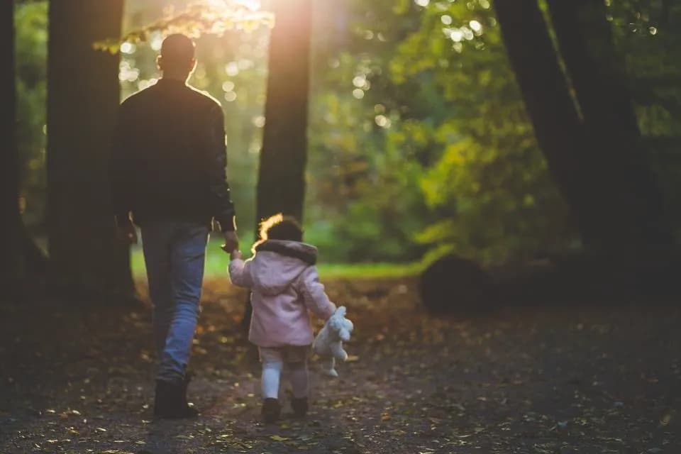 Un père marche avec sa fille en forêt