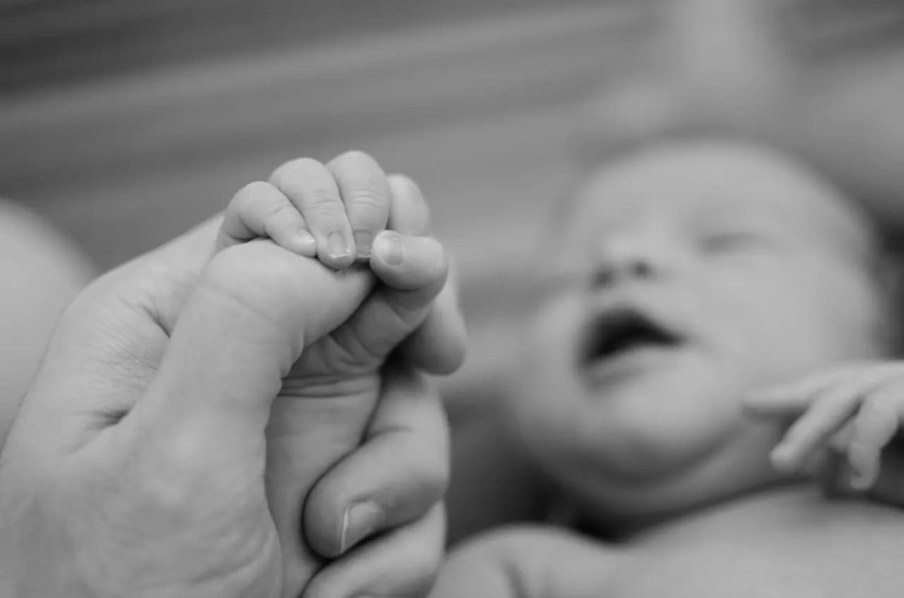 Un bébé serre le doigt d'un adulte