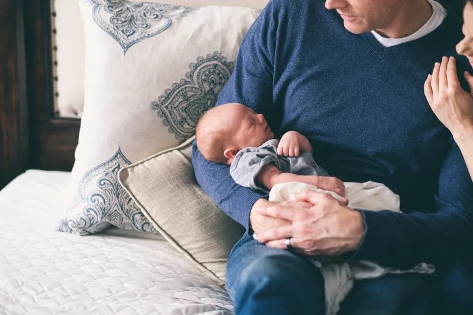 Un père tient son nouveau-né endormi contre lui