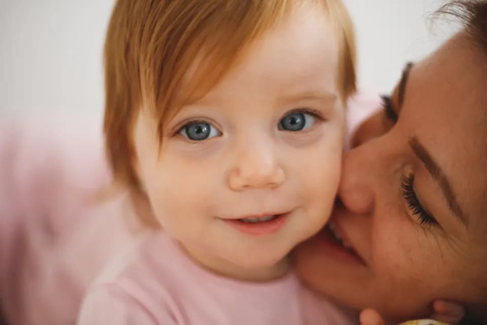 Une mère embrasse sa petite fille souriante